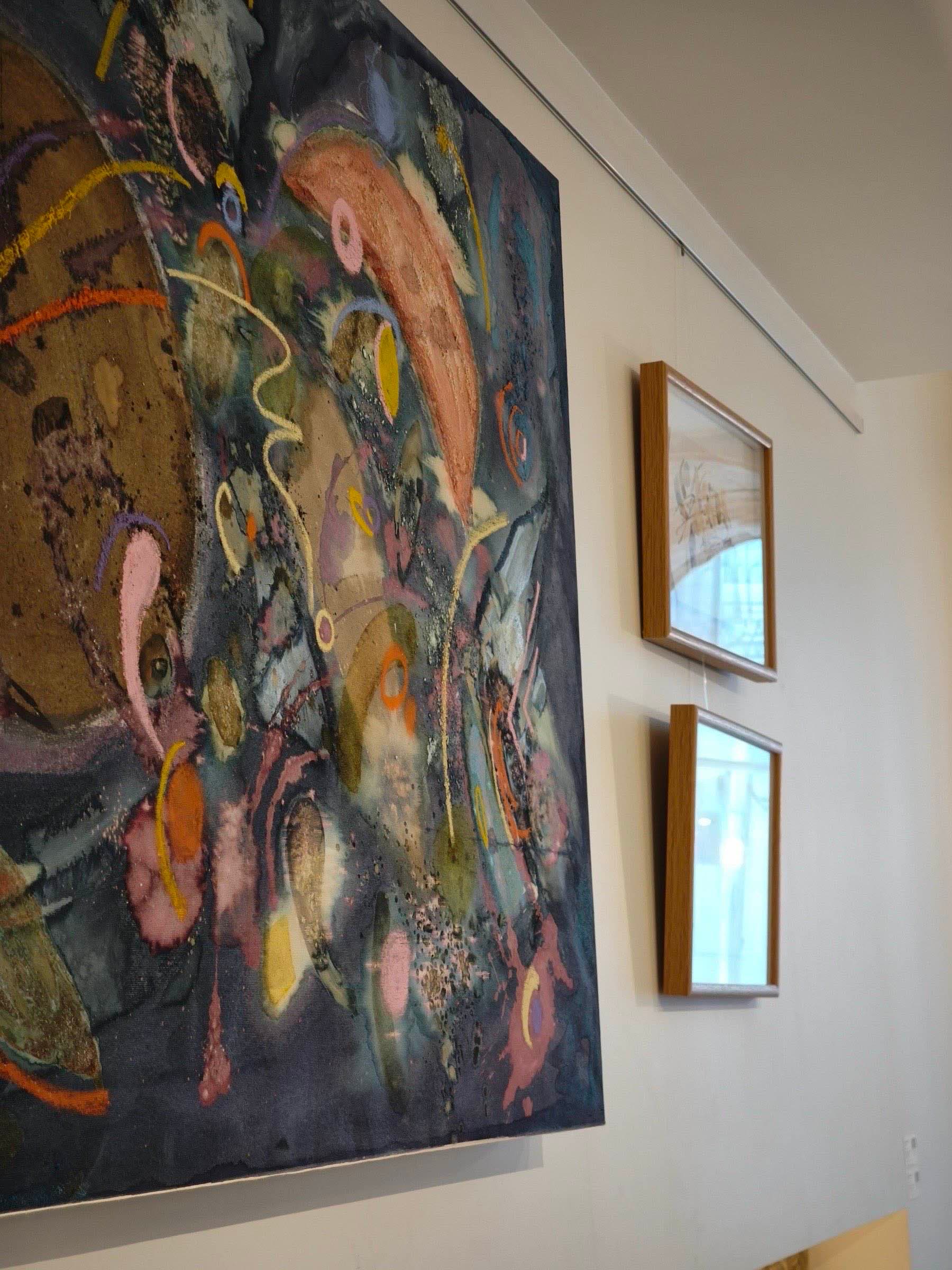 Angled view of a large painting by Bianca Castro beside two small framed works, Matéria Viva